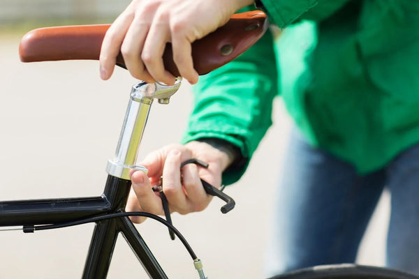 Personne tenant une selle marron et utilisant une clé hexagonale au niveau du collier de la tige de selle.
