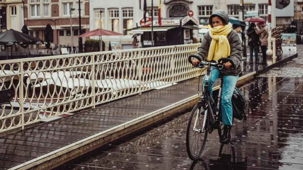 Cycliste roulant sur un pont sous la pluie, sur une chaussée mouillée.