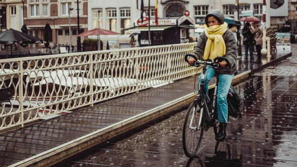 Cycliste roulant sur un pont sous la pluie, sur une chaussée mouillée.